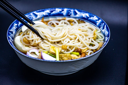Noodles with meat and vegetables in a bowl on a black backgroundの写真素材