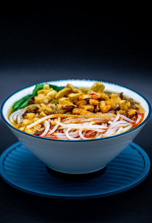 Noodles with chicken and vegetables in a bowl on a black backgroundの写真素材