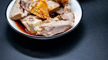 Boiled pork with sweet and sour sauce in bowl on black backgroundの写真素材