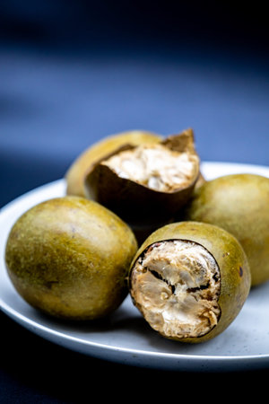 Fresh shelled and unshelled macadamia nuts on a white ceramic plate.