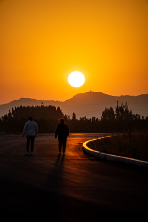 Couple walking on the road in the mountains at sunset time.の写真素材