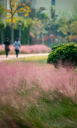 Blurred background of grass and flowers in the park with people walkingの写真素材