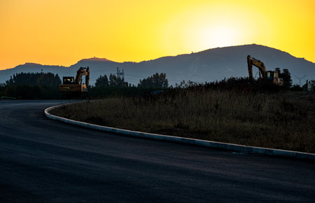 Backhoe working on a road at sunset in the mountains. Toned.の写真素材