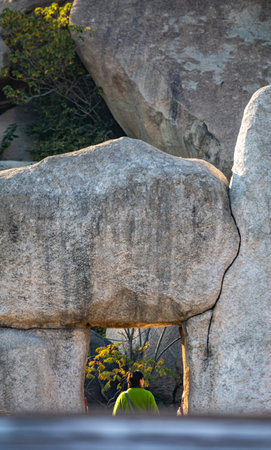 Man looking through the window of a stone cave in the park.の写真素材