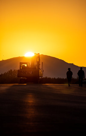 Silhouette of workers on road construction site at sunset time.の写真素材
