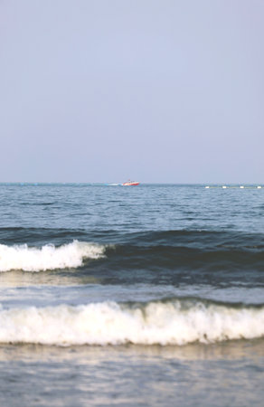 Boat in the sea with waves on the sand and cloudy skyの写真素材