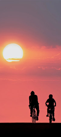 Silhouette of a man and woman riding bicycles at sunset.の写真素材