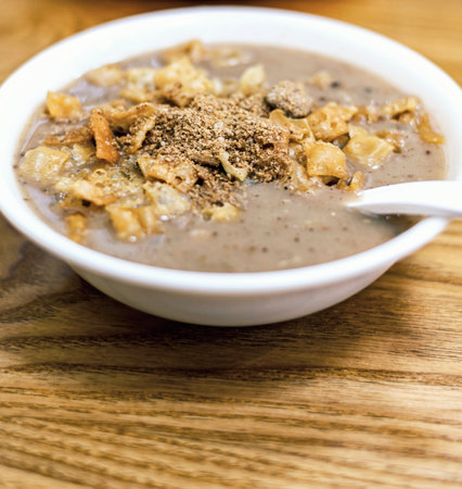 Bowl of porridge with croutons on wooden tableの写真素材