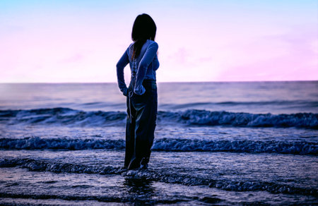 Silhouette of young woman standing on the beach at sunset.