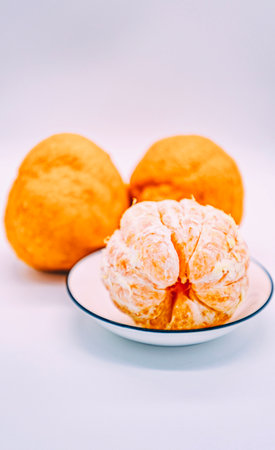 Peeled tangerines on a white plate on a white backgroundの写真素材