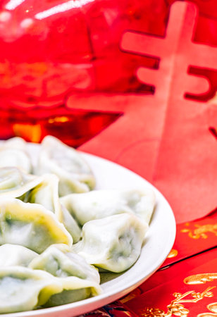 Chinese dumplings on a white plate with red envelopes and red lanternの写真素材