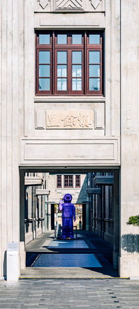 A man in a purple coat is standing in front of the entrance to the building in Sarajevo.の写真素材