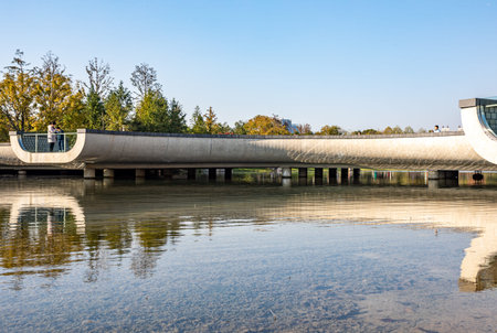 Modern concrete bridge over the lake in the city park, autumn landscape