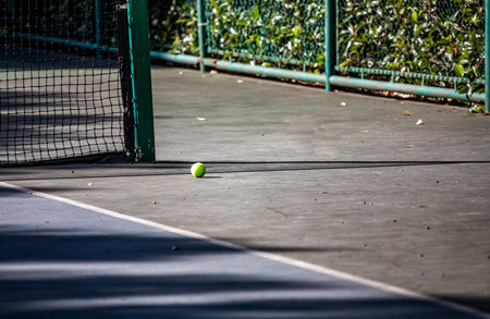 Tennis ball on a tennis court with a net in the background