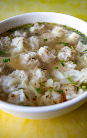 chicken dumplings soup in a bowl on a yellow background