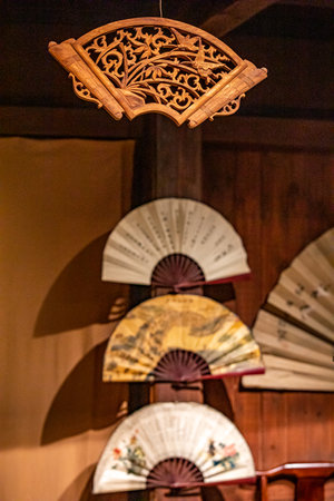 Wooden hand fan hanging on a wooden wall in a restaurant.の写真素材