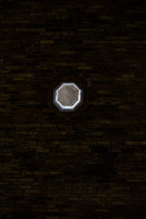 Hexagonal light on a brick wall in a dark room.