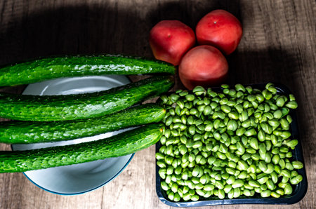Cucumbers, tomatoes and peaches on a wooden table.の写真素材