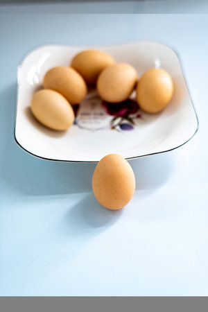 Eggs in a white plate on a blue background, top view