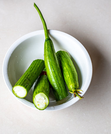 Cucumbers in a white bowl on a light background. Selective focus.
