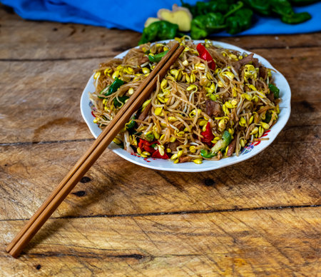 Stir fry noodles with pork and vegetables in a bowl on wooden tableの写真素材