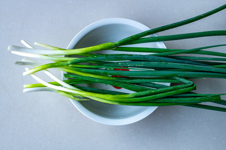 Green onion in a white bowl on a gray background, top viewの写真素材