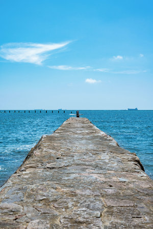 Pier in the sea with blue sky and white clouds background.