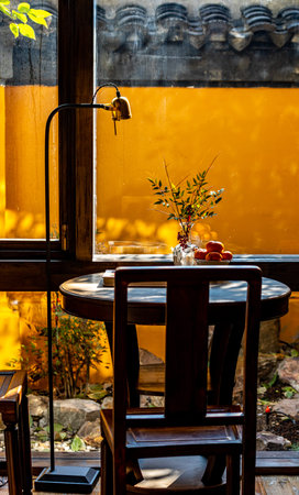 Wooden table and chairs in a cafe with yellow wall background.