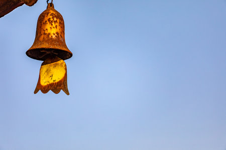 Old bell hanging on the wall with blue sky background, Thailand.の写真素材