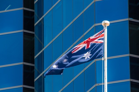Flag of Australia waving in light breeze in front of modern skyscraperの写真素材