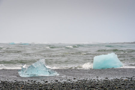 Diamond beach black sand crystal clear blue pieces of ice on beach and in the sea