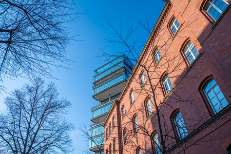Old red brick building in front of architectural modern office building and a blue clear sky