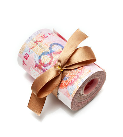 Roll of chinese yuan banknotes tied with gold ribbon isolated on whiteの写真素材