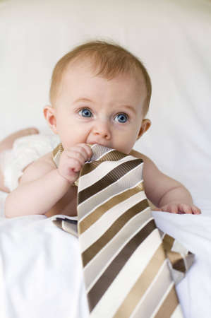 Young baby girl with tie around her neck on a white backgroundの写真素材