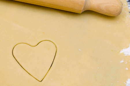 The shape of a heart pressed on a fresh sheet of cookie doughの写真素材
