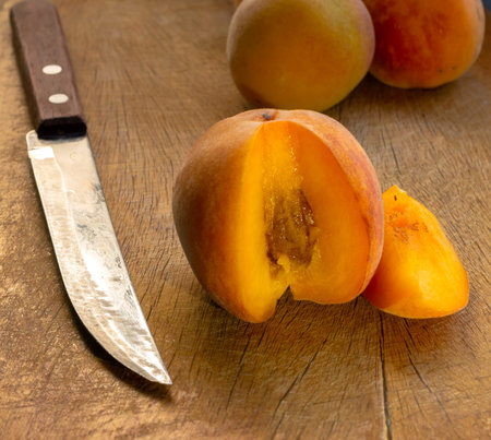 peachs on a brown choppingboard with a knife