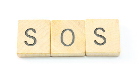 SOS spelled out of wooden blocks isolated on white.
