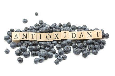 Blueberries on a white background with Antioxidant spelled out in wooden blocks.