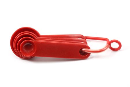 Red measuring spoons on a white background.の写真素材