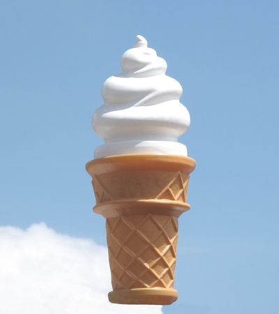 A giant vanilla ice cream cone in the blue sky.の写真素材