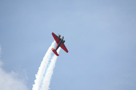 A red airpline is sky writing against a blue sky.
