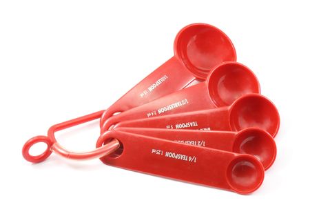 A set of red measuring spoons photographed on a white backgroundの写真素材