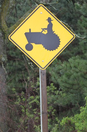 A yellow and black tractor crossing road sign.の写真素材