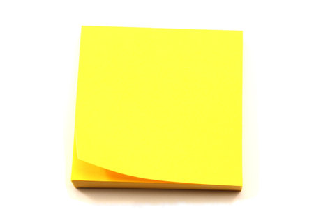 A stack of yellow sticky note pads with a corner turned up.