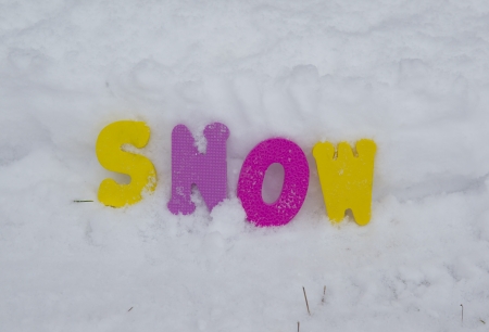 Colorful yellow, pink, and purple letters spell out snow against a big pile of freshly fallen white snow.の写真素材