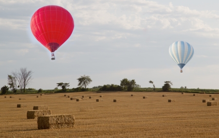 Red and Blue Hot Air Balloons over Fresh Hay Field baled の写真素材