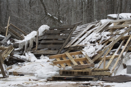 A stack of wooden pallets outside a landfill piled up in the snow.の写真素材