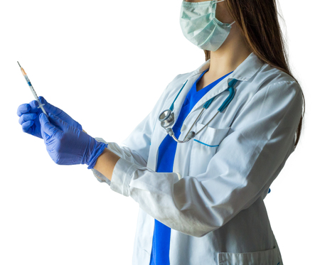 Unknown female doctor in medical uniform with mask holding a syringe ready for injection. Caucasian female model isolated over white background.の写真素材