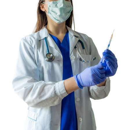 Unknown female doctor in medical uniform with mask holding a syringe ready for injection. Caucasian female model isolated over white background.の写真素材