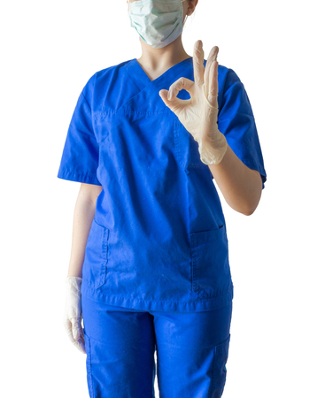 Unknown young female doctor in blue medical uniform showing ok sign with sterilized surgical gloves. Caucasian female model isolated over white background.の写真素材